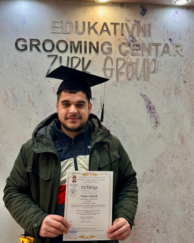 Momak ponosno drži diplomu nakon završenog kursa za šišanje pasa.